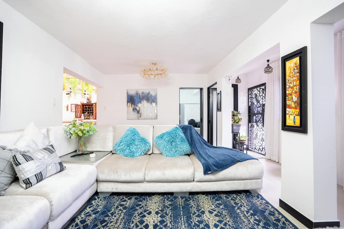 A living room with a sofa, a coffee table, a chandelier, and artwork on the walls.