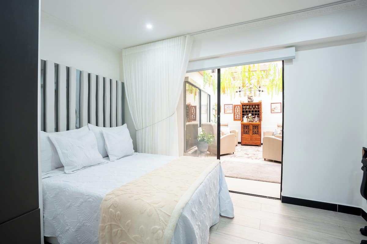 A bedroom with a bed, a sliding glass door leading to a patio area with furniture.