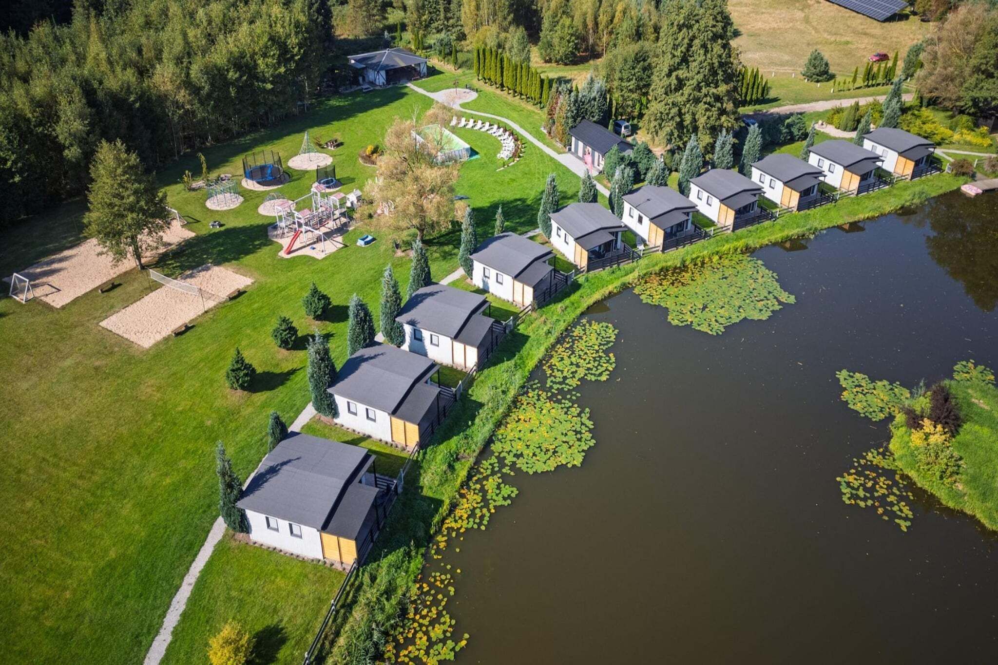 Un quartier résidentiel bordé de maisons, situé le long d’un plan d’eau et entouré de verdure et d’arbres.