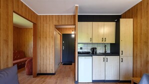Ett kompakt bostadsutrymme med ett litet kök, en soffa och en matplats.