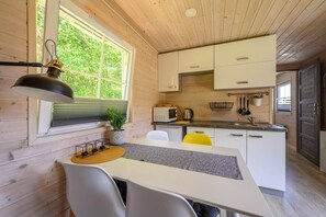 Eine kompakte Küche mit Holzwänden, einer weißen Arbeitsplatte und einem Essbereich mit Tisch und Stühlen.