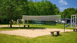 A playground with a netted play area, a slide, and a bench. - Holiday cottage no. 2A with private jacuzzi (Darlowo)