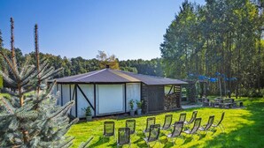 A building with a sloped roof, surrounded by a grassy area with chairs and a small table. - Holiday cottage no. 2A with private jacuzzi (Darlowo)
