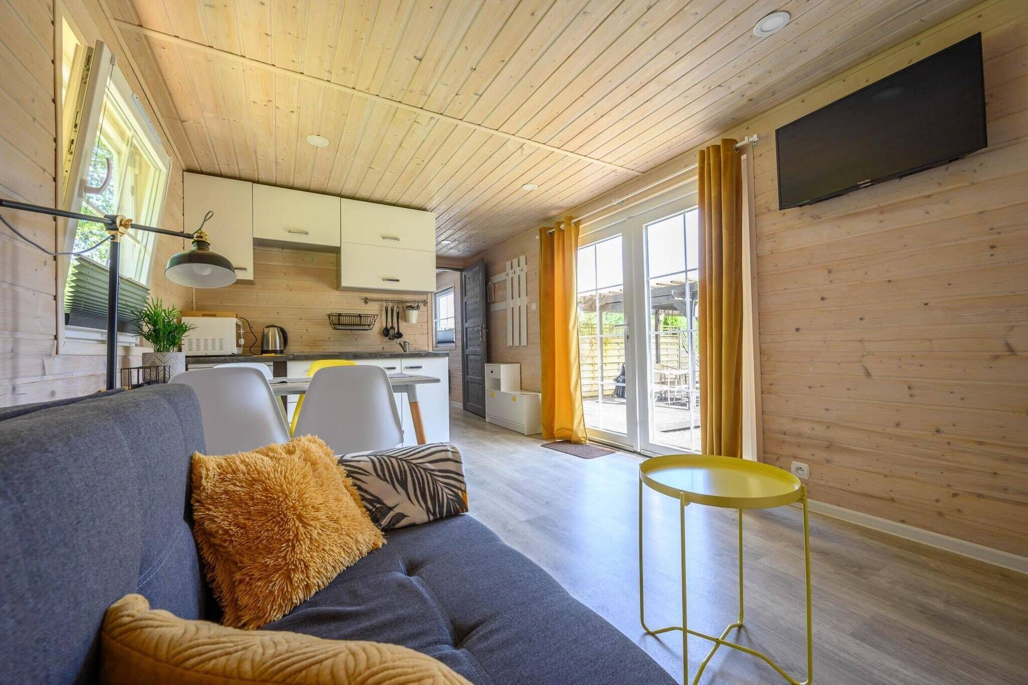 Un intérieur moderne comprenant un canapé, une petite table ronde et un coin cuisine avec des placards et un téléviseur.