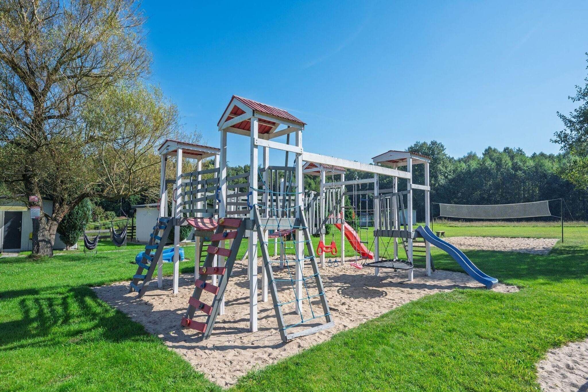 Une aire de jeux avec une structure d’escalade, des toboggans et une balançoire.