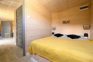 A room with a bed, a wooden wall with a 'RELAX' sign, and a door leading to another room. - Holiday cottage no. 4A with private jacuzzi (Darlowo)