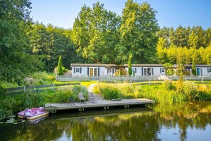 A lakeside cabin with a dock, surrounded by lush greenery and trees. - Holiday cottage no. 4A with private jacuzzi (Darlowo)