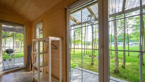 A wooden interior with large windows, a white shelving unit, and a view of a green landscape. - Comfortable holiday home no. 2B with a fireplace (Darlowo)