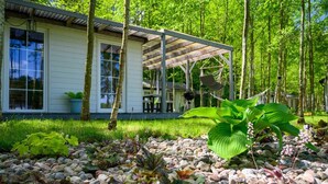 A modern house with a covered patio, surrounded by a garden with various plants and a gravel path. - Comfortable holiday home no. 2B with a fireplace (Darlowo)