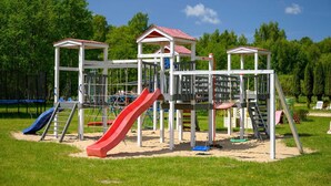 A playground with a red slide, climbing structures, and a covered playhouse. - Comfortable holiday home no. 3B with a fireplace (Darlowo)