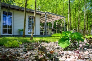 A modern house with a covered patio, surrounded by a garden with various plants and a gravel path. - Comfortable holiday home no. 3B with a fireplace (Darlowo)