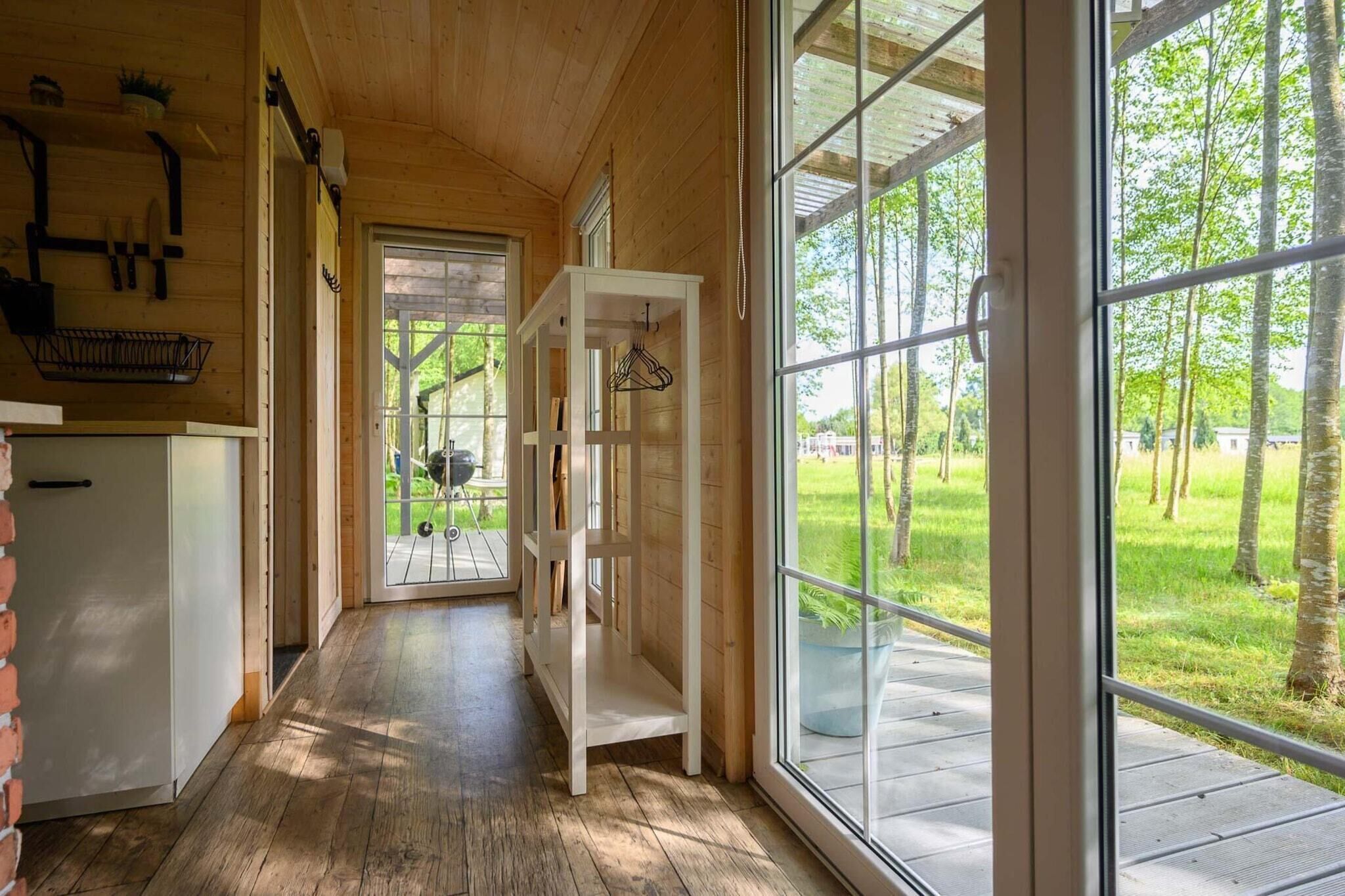 Un intérieur en bois avec une grande fenêtre, un luminaire suspendu et une vue sur l’extérieur.