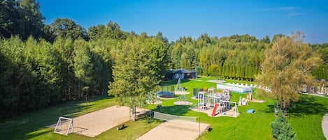 Un parc avec une aire de jeux, un but de football et un bâtiment en arrière-plan.