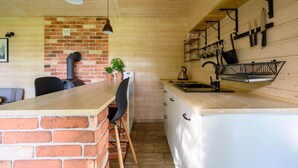 A kitchen with a brick wall, wooden cabinets, a sink, and hanging utensils. - Comfortable holiday home no. 3B with a fireplace (Darlowo)