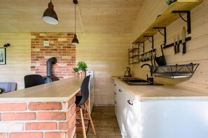 Eine Küche mit Backsteinwand, Holzschränken, einem Spülbecken und hängenden Küchenutensilien.