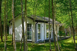 A small, single-story cabin with a sloped roof, surrounded by a forest. - Comfortable holiday home no. 4B with a fireplace (Darlowo)