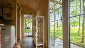 Un intérieur en bois avec une grande fenêtre, un luminaire suspendu et une vue sur l’extérieur.