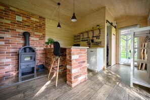 A rustic kitchen with a brick fireplace, wooden ceiling, and a view of the outdoors. - Comfortable holiday home no. 4B with a fireplace (Darlowo)
