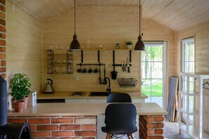A rustic kitchen with wooden walls, a brick counter, hanging utensils, and a large window. - Comfortable holiday home no. 4B with a fireplace (Darlowo)