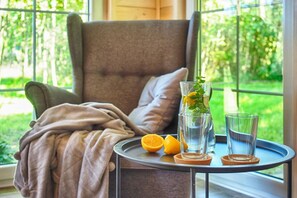 A cozy seating area with a cushioned chair, a table with a glass of water, a glass of a beverage, and a slice of orange. - Comfortable holiday home no. 4B with a fireplace (Darlowo)