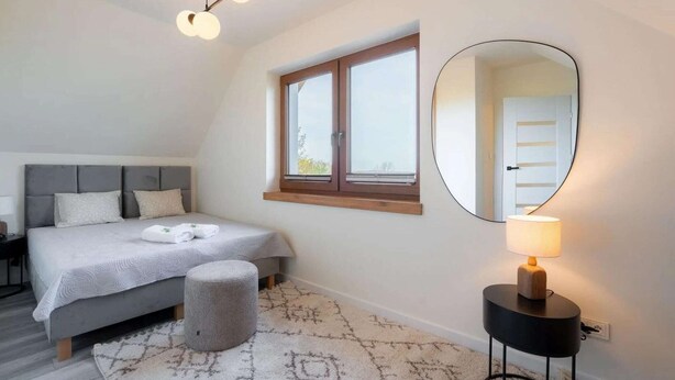 A bedroom with a bed, bedside table, lamp, and a window. - Comfortable holiday villa, sauna, jacuzzi (Marcyporeba)