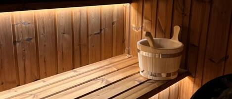 A wooden bench with a wooden bucket and a wooden spoon leaning against a wooden wall.