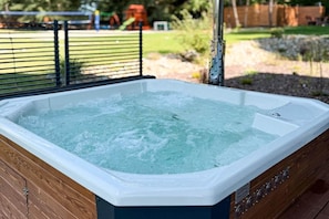 A hot tub with a wooden frame and a metal railing. - Large holiday villa with garden, sauna and jacuzzi (Marcyporeba)