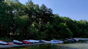 A calm river with boats docked along the bank, surrounded by dense trees.