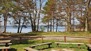 Un parc au bord du lac, équipé de tables de pique-nique et agrémenté d’arbres.