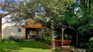 Une maison avec une terrasse en bois, un petit porche et une cour gazonnée.