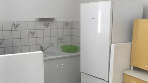 Una cucina con un frigorifero bianco, un lavello e una bacinella verde.