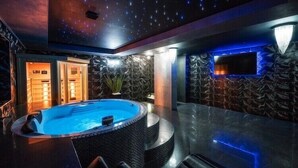 A modern indoor pool area with a hot tub, seating, and a starry ceiling design.