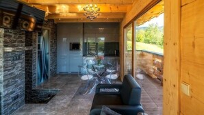 A modern interior with a stone fireplace, a dining area with clear chairs, and a view of the outdoors.