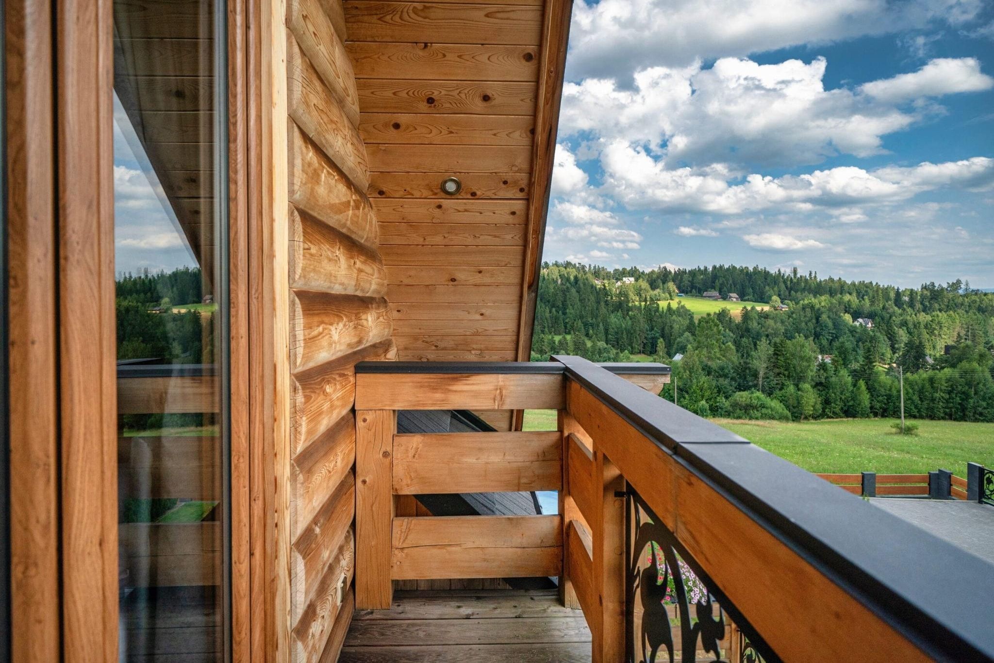 Un balcón de madera con vistas a un paisaje boscoso.