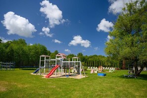 A playground with slides and climbing structures, surrounded by trees and grass. - Single-story holiday home by the pond no. 2 (Darlowo)