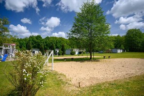 A playground with a slide and climbing structures, a fenced area with benches, and a building with a red roof. - Single-story holiday home by the pond no. 6 (Darlowo)