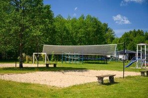 A playground with a netted play area, a slide, and a bench. - Single-story holiday home by the pond no. 8 (Darlowo)
