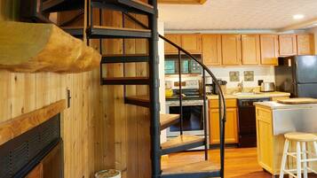 Un intérieur en bois avec un escalier en colimaçon, un coin cuisine et un espace repas.