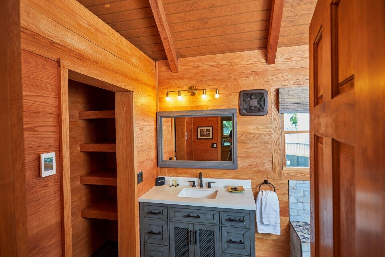 Une salle de bain en bois avec un lavabo intégré, un miroir et un porte-serviettes.