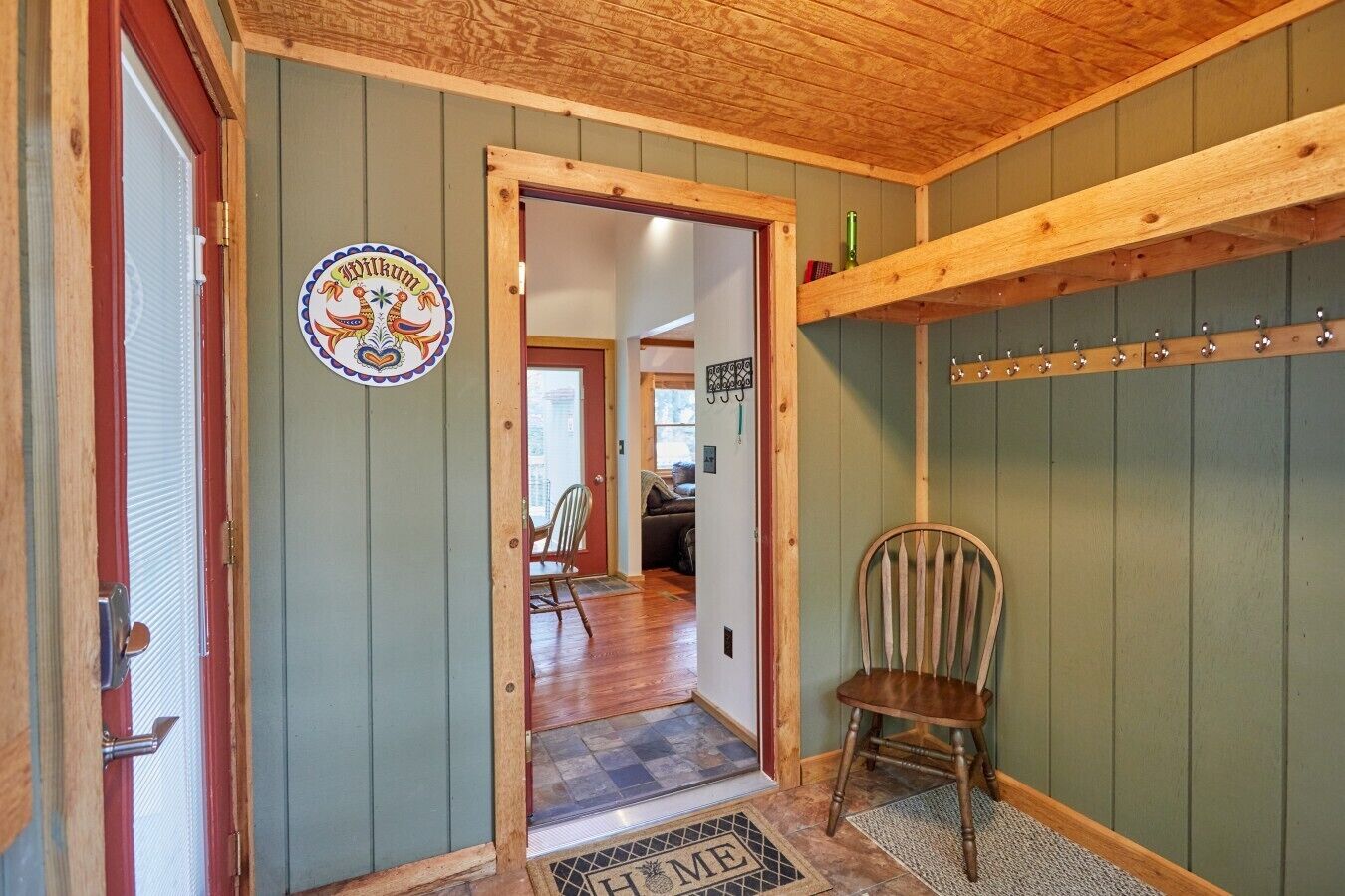 A wooden interior with a door, a coat rack, and a chair.
