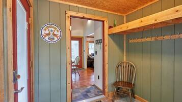 A wooden interior with a door, a coat rack, and a chair.