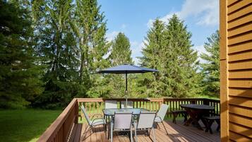 Une terrasse en bois avec une table et des chaises, entourée d’arbres.