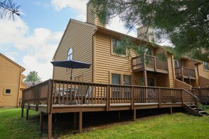 A two-story wooden house with a deck, a balcony, and a staircase. - Deerfield Village | Sleeps 10 | Fireplace + Pool (Tucker County)