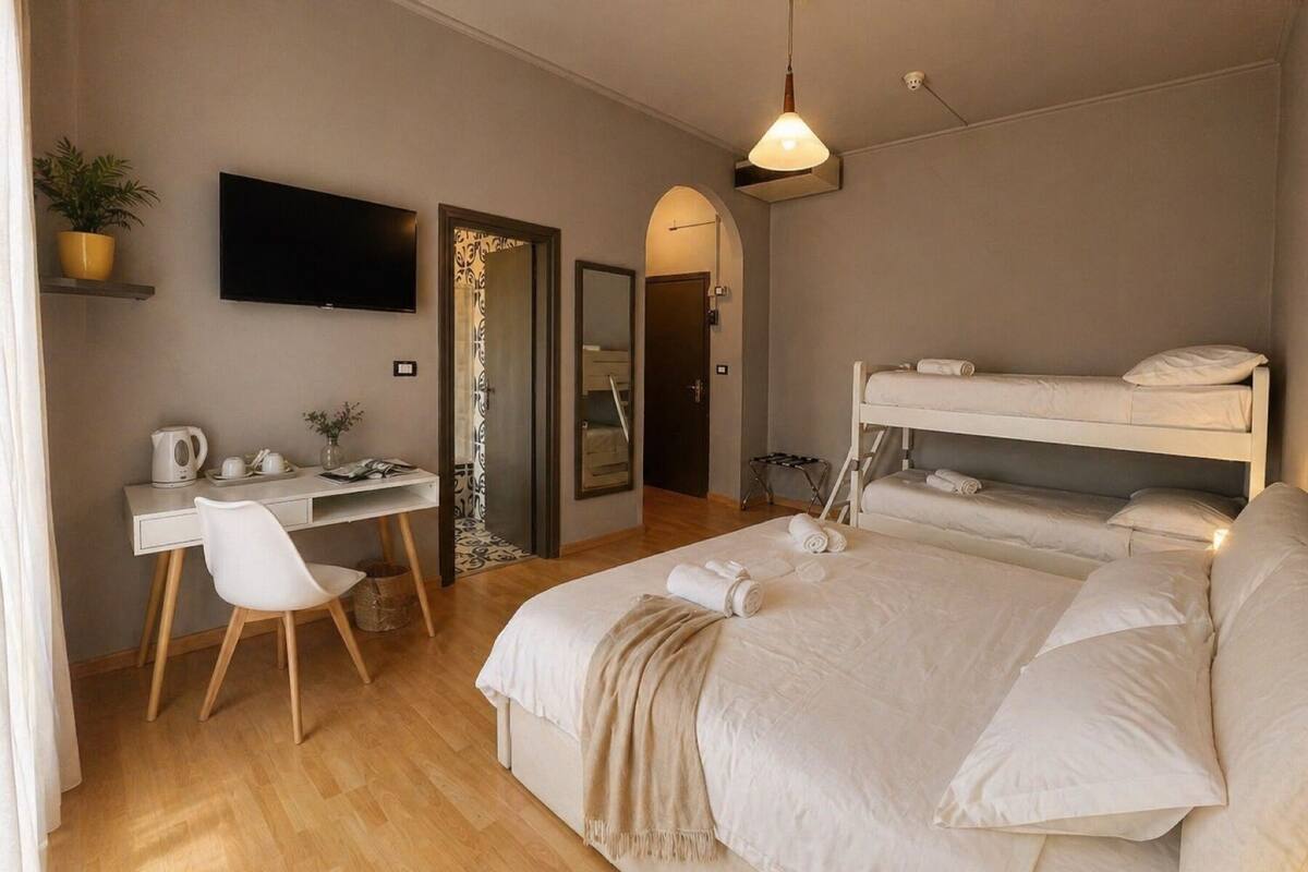 A bedroom with a bed, a desk, a chair, a television, and a bunk bed.