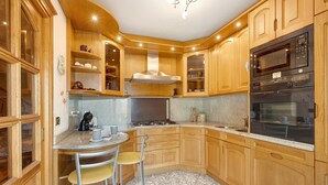 A kitchen with wooden cabinets, a built-in stove, and a microwave. - 'Terrazza Valtellina' Apartment with Mountain View, Shared Terrace, and Wi-Fi (Grosio)