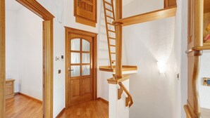 A wooden staircase with a handrail, a door with glass panels, and a light switch on the wall. - 'Terrazza Valtellina' Apartment with Mountain View, Shared Terrace, and Wi-Fi (Grosio)