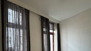 Ein Schlafzimmer mit einem Bett, einem Fenster mit Vorhängen und einer Deckenleuchte.