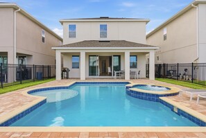 Ein Swimmingpool mit Whirlpool, umgeben von einer Terrasse mit Gartenmöbeln.
