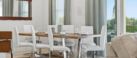 A dining area with a wooden table, white chairs, and a large mirror.