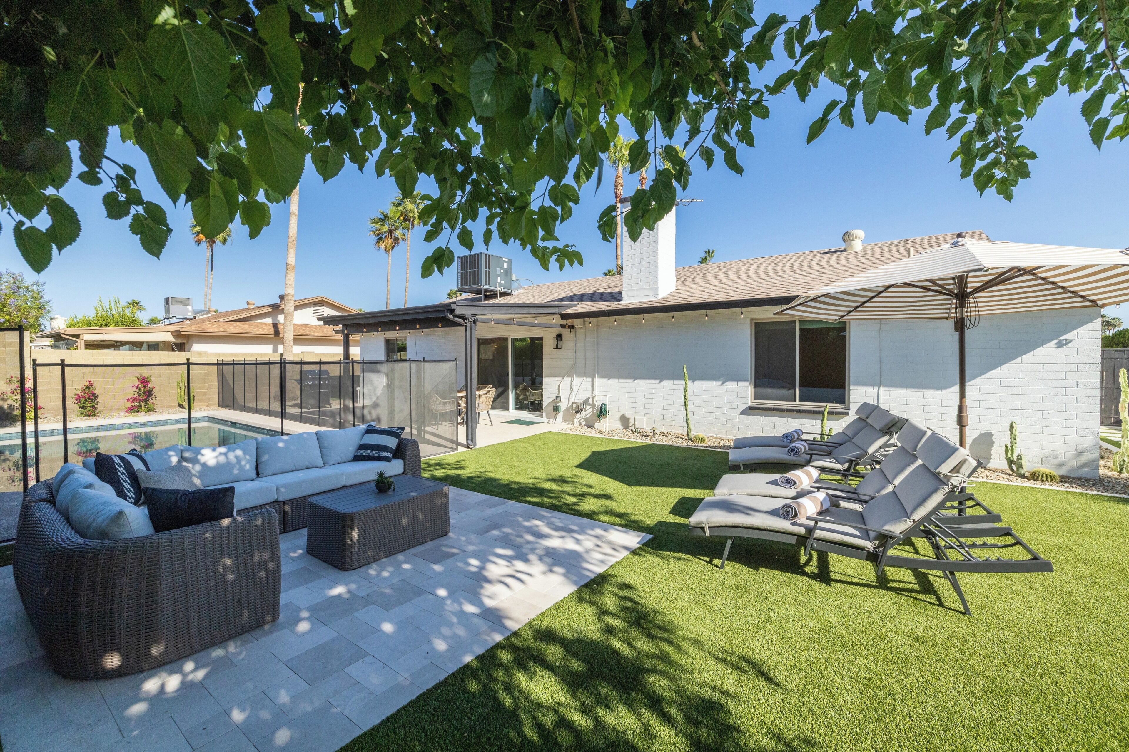 A modern house with a swimming pool, outdoor seating, and a well-maintained lawn.